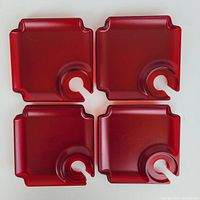 Four red small square melamine appetizer plates with integrated round drink holders on one corner, arranged top-down to show the plate design and holder shape.