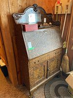 Front view showing carved crest, mirrored panel, drop-front closed, and lower cabinet