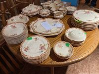 Full overview of Victorian Johnson Bros china set arranged on table, showing multiple pieces including plates, bowls, saucers, teacups, and serving pieces with floral design.