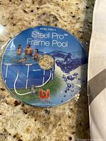 Steel Pro Frame pool DVD manual/photo with product branding showing family swimming and pool details