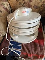 Full view of the Nesco American Harvest food dehydrator showing four white circular stackable trays, white base, and attached white power cord.