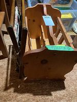 Wooden magazine rack showing the side and bottom view with dimensions taped on the side.