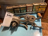 Photo of the meat grinder positioned in front of a row of six vintage spice containers with labels visible.