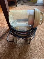 Side view of Aqua Leisure pool filter pump showing clear plastic cylindrical housing and beige base with attached black power cord.