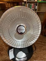 Front view of Presto HeatDish heater showing parabolic metal reflector and protective grill with brand markings.