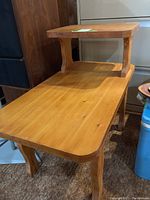 Full side view of the wooden end table showing two-tier surfaces and curved legs.