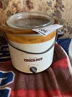 Full view of Rival Crock-Pot slow cooker showing ceramic stoneware insert, glass lid, and metal handle.