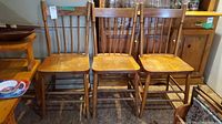 Front view of three vintage solid wood spindle back chairs side by side