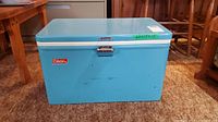 Front view of blue vintage Coleman cooler with metal latch and label.