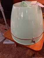 Photo of the vintage Kenmore electric hair dryer, mint green cone shape with metal ring and latch on base, showing front and side angles.