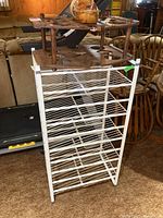 Three different wine racks stacked together showing various designs and materials: white wire rack, wooden decorative rack, and shoe bottle holder.