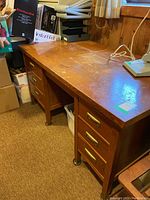 Full view of the wooden desk showing the surface and drawer layout with visible scratches.