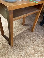 Close-up of the table leg and side of tabletop showing wood grain and shelf detail