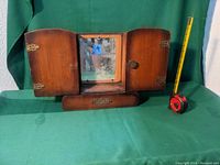 Front view of closed antique wooden medicine cabinet with mirror and drawer, including measuring tape for scale.
