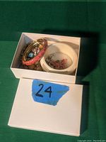 Box containing assorted costume jewelry including bracelets and small jewelry items in a dish.
