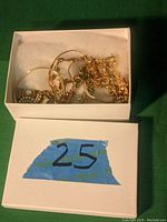 Box containing several gold-tone chains and necklaces jumbled together