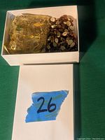 Box of mixed costume jewelry pieces including a gold-tone mesh item and a multi-strand beaded necklace.