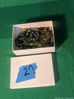 White box with blue tape marked 27 containing green bead jewelry.
