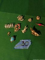 Full set of assorted decorative pins and brooches arranged on green background with lot number 30 visible.