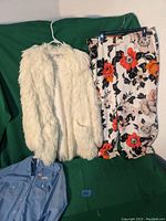 Full view of vintage white fluffy Saks Fifth Avenue cotton coat, floral pants, and embroidered cat blouse folded below