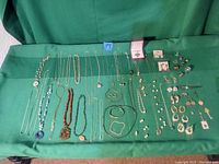 Full collection of sterling silver jewelry displayed on green fabric, showing necklaces, bracelets, rings, earrings, and pendants.