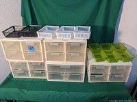Photo showing multiple stackable beige plastic storage drawer units with semi-transparent drawers. On top small black, white, and green plastic storage baskets are placed.