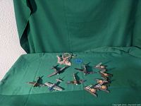 Photo showing a collection of 11 toy planes of various sizes and colors arranged on a green cloth. Includes metal and plastic planes with military markings and a larger helicopter-like plastic model.