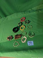 Overview of eleven assorted bracelets on green fabric background showing variety in style and color.