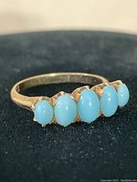 Front view showing five oval turquoise stones on gold band