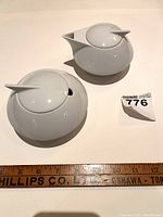 Top view of the cream and sugar set showing lids and overall shape on a white surface with measurement ruler beneath.