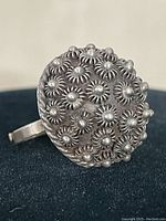 Close up of sterling silver ring's floral dome design showing detailed raised flowers on rounded top.
