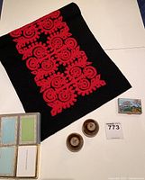 Photo showing Hungarian felt table runner (black with red embroidery), pair of lucite salt and pepper shakers, small enamel pill box, and Tiffany & Co. playing cards