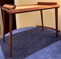 Full view of the 1960s mid-century Danish folding side table standing upright, showing four slender tapered legs and a rectangular tray-like top with raised edges on two sides.