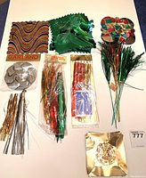 Photo showing several foil garlands including a multicolored square shaped garland, a green folded foil garland, a plaid star garland, and silver spiral ornament with several bundled tinsel sprays, some still in package.