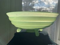 Side profile view of the jadeite candy bowl showing its ribbed pattern, flared rim, and three legs.