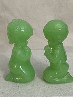 Front view of the two green jadeite jade figurines, a boy and a girl, kneeling in praying posture.