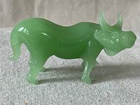 Side view of the jadeite water buffalo figurine showing its polished green surface and detailed carving.