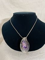 Full view of necklace displayed on black bust showing chain and pendant with purple glass stone.