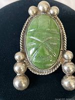 Front view of the vintage sterling silver brooch highlighting the carved green onyx face and silver bead detailing.