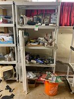 Grey plastic shelving unit filled with assorted hardware, fittings, paints, copper pipes, and boxes.