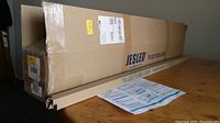 Box with JESLED T8 LED Tube Lights branding and installation instructions on table.