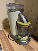Side angle view of the Margaritaville margarita drink maker showing the pitcher, handle, spout, and power cord wrapped around the base.