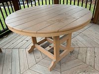 Overall view of round patio table with composite wood plank-style top and sturdy base, showing central umbrella hole capped.