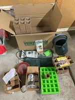 Photo of entire box showing large plastic watering can, peat pots in strips, seed pellet packaging, green seedling tray, heat mat, compressed moss, and fountain filters with packaging.