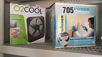 Both boxed items on a shelf: Wagner 705 Power Steamer and O2 Cool 10-inch portable fan.