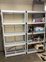 Photo showing two white plastic storage shelf units with five shelves each, partially filled with various household and pet items, positioned against a wall.