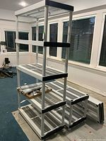 Plastic shelving unit assembled with nine slatted shelves and black corner accents, standing on blue floor.