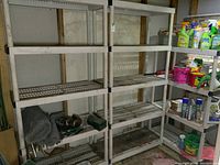 Photo showing two taller plastic shelving units with five shelves each, white color, slat design, with some dirt and wear.