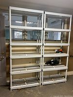Front view of two assembled white plastic collapsible shelving units side by side, each with six shelves and supporting vertical posts.