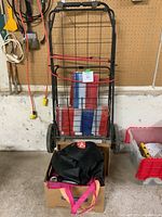 Photo of black metal wire folding shopping cart with reusable bags inside and red bungee cords attached